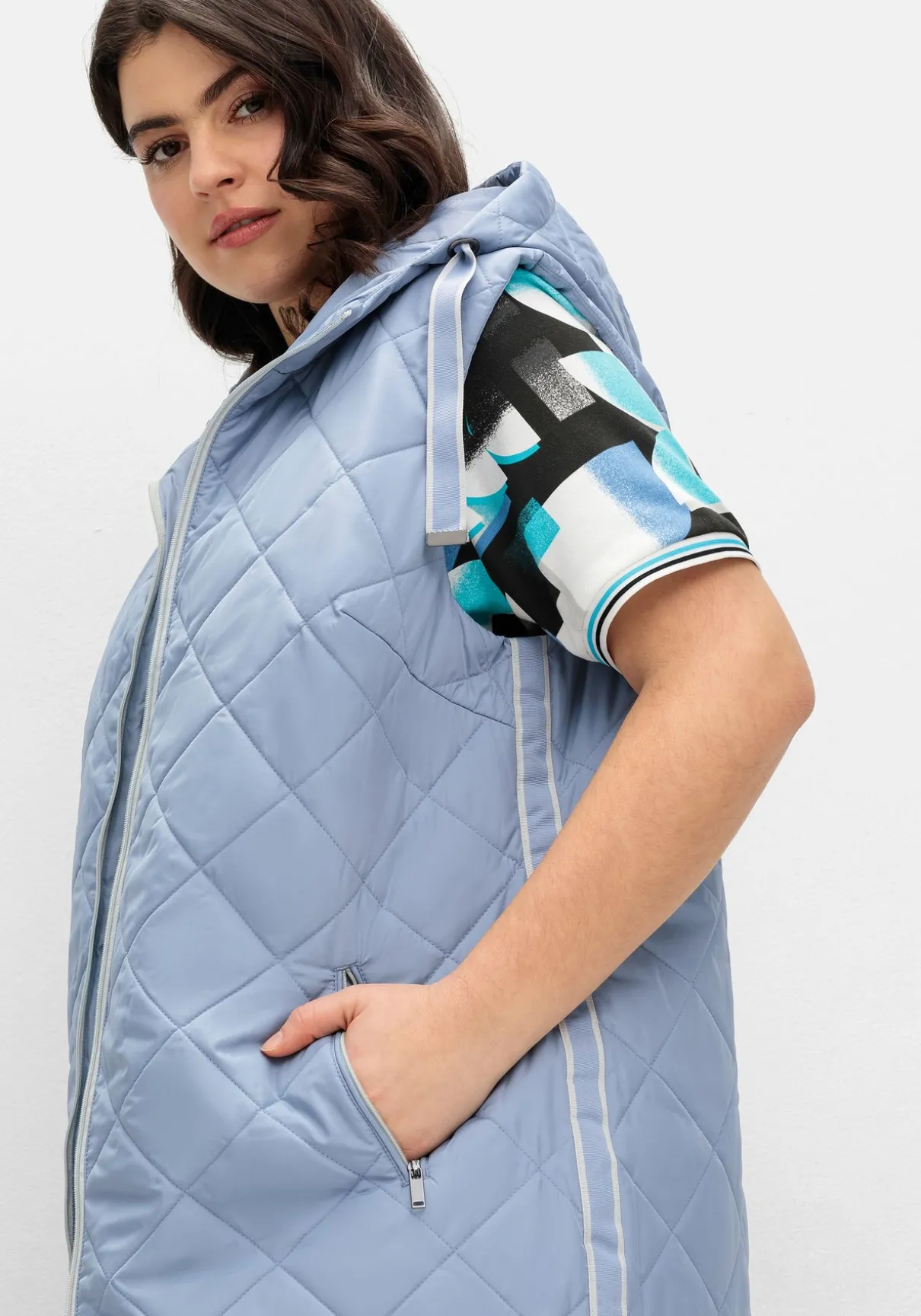 Lange Steppweste mit Kapuze und Kontrastdetails